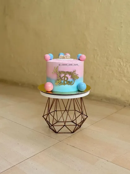 A sweet pink and blue "Mommy to be" cake decorated with colorful balls. A lovely centerpiece for a baby shower.