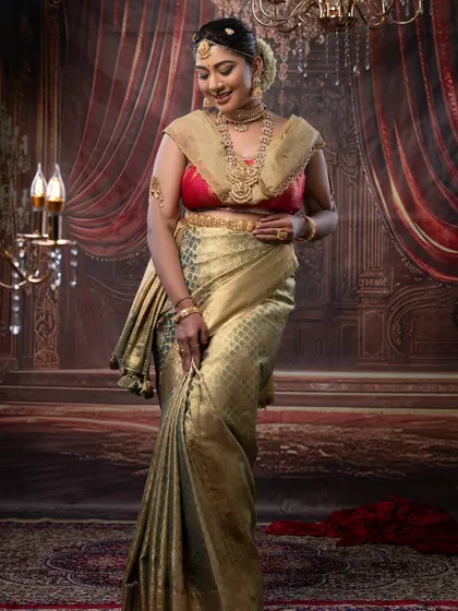 A full-length portrait of a bride in a stunning gold and red ensemble. The makeup is warm and glowing, perfectly complementing her attire.