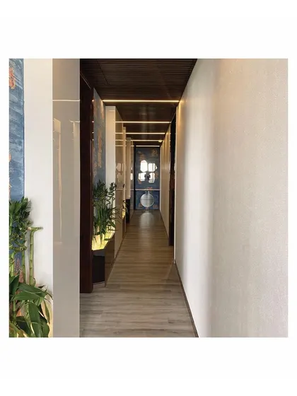 The completed corridor, showing the effect of the linear cove lighting on the ceiling and the texture of the wall finishes. The design successfully transforms a simple passage into an elegant experience.