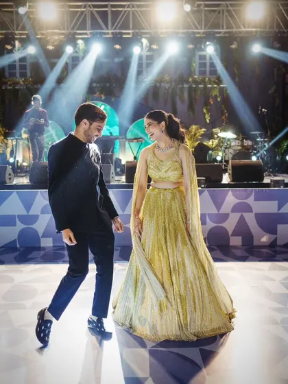 The couple shares a dance on a custom-printed dance floor, with the live band and stage lights in the background, capturing a candid moment of joy.