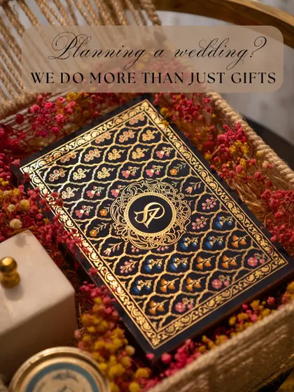 We do more than just gifts; we create the first impression for your entire wedding. This image showcases one of our signature invitation cards, featuring a rich, traditional design with a custom gold-foil monogram.