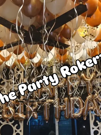 A closer look at the ceiling balloon decoration, showing the mix of chrome and latex balloons with hanging ribbons for a full and festive effect.