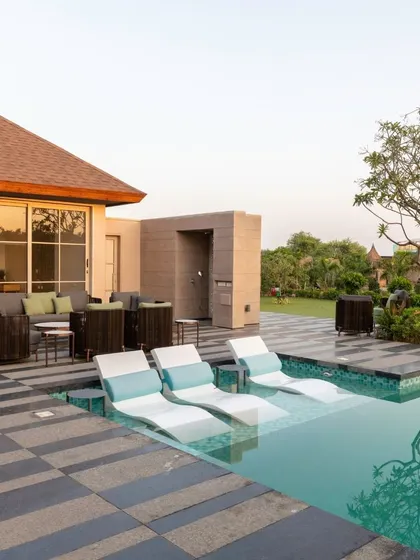 We design spaces that seamlessly connect the indoors with the outdoors. This poolside lounge area features comfortable seating and in-pool loungers, creating a perfect retreat for relaxation and entertainment.
