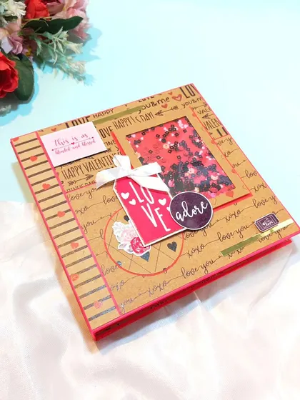 This love-themed scrapbook with a shaker window is a perfect gift for Valentine's Day. It's designed with rustic kraft paper and pops of red to create a warm, romantic feel.