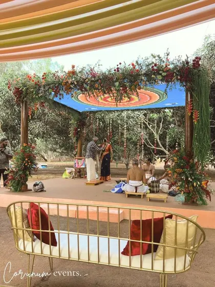 The mandap for a backyard wedding, featuring a custom mandala ceiling and rustic floral decor, perfectly framed by the surrounding trees.