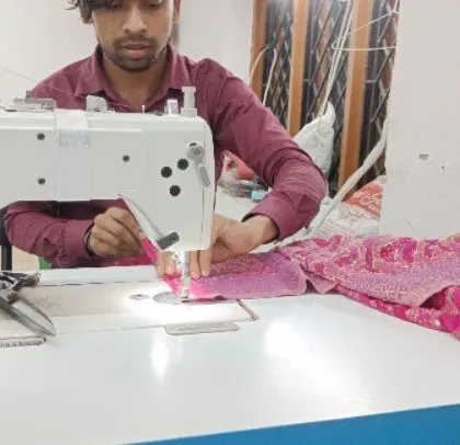 An expert tailor at the sewing machine, stitching a heavily embroidered fabric. Precision is key, especially when working with delicate and detailed materials.