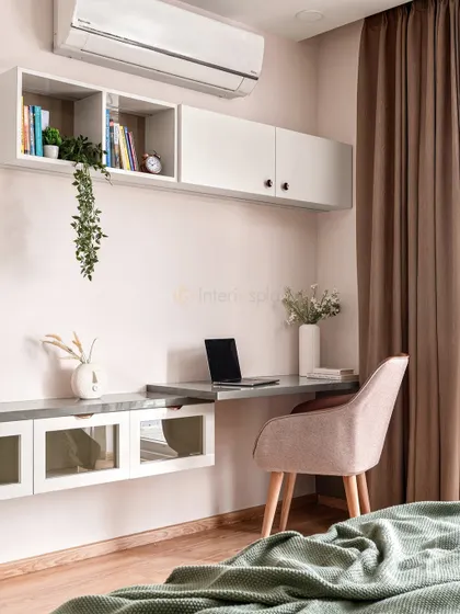This master bedroom includes a functional workspace with a floating desk and overhead storage. The neutral tones and natural textures create a calm and productive environment.