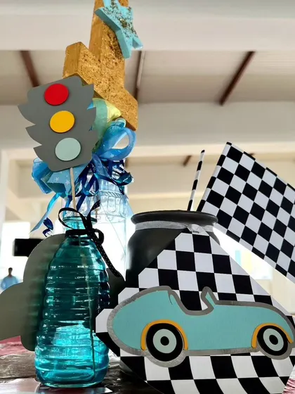 A custom centerpiece for the Dinky Car party, featuring a traffic light, a checkered flag, and a vintage-style toy car. Every table gets a touch of the theme.