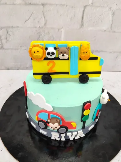 A sweet and playful cake for a 2nd birthday. This design features a school bus full of cute fondant animals, a little car, and traffic lights to create a fun road scene.