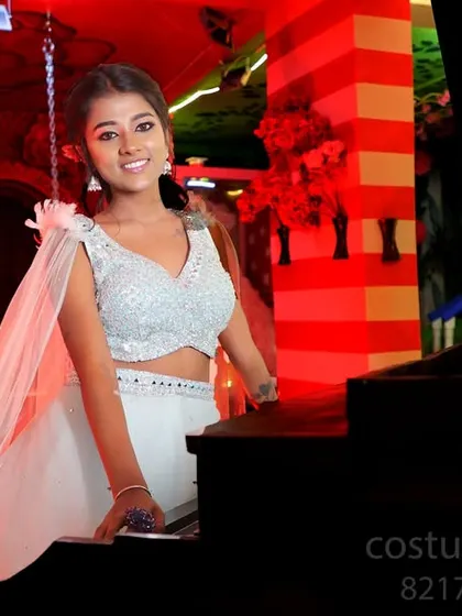 A smiling portrait of the model by the piano.
