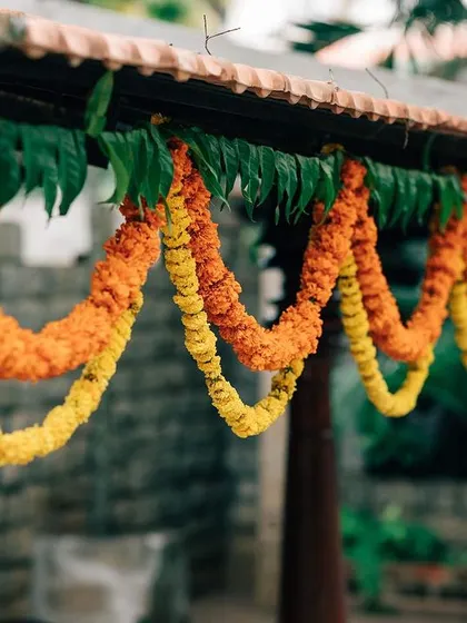 Traditional marigold torans (garlands) hang from the tiled roof of the venue, enhancing the heritage feel of the space.