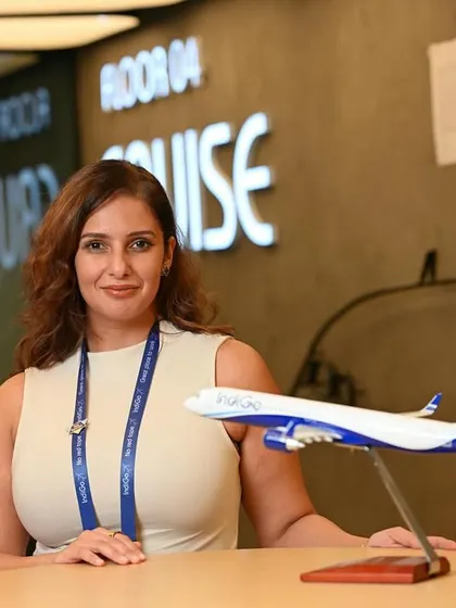 A branding shot for IndiGo Airlines, featuring an employee with a model aircraft. This visually reinforces the company's industry and brand.
