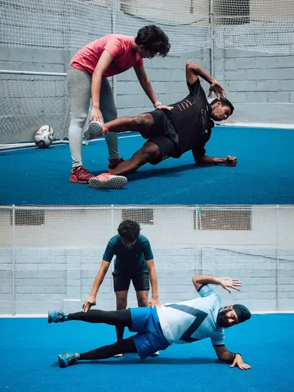 Coaches assisting athletes with a challenging side plank variation. This highlights the personalized attention and support provided to ensure safety and effectiveness in every drill.