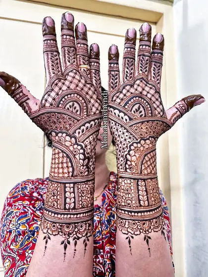 Here is a beautiful example of symmetrical bridal mehndi, where both hands mirror each other. The design features classic Indian architectural arches and fine net patterns, known as jaali, for a truly intricate look.