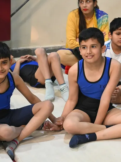 A candid moment between two young gymnasts, sharing a conversation during a break.