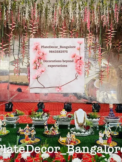A stunning display of seer platters for a wedding, set against a backdrop of hanging flowers. The setup includes my decorated jewellery platters and traditional doll arrangements.