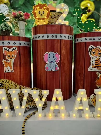 Close-up of the decor for Avyaan's jungle party, showing light-up letters spelling his name in front of barrel-style pedestals with cute animal stickers.