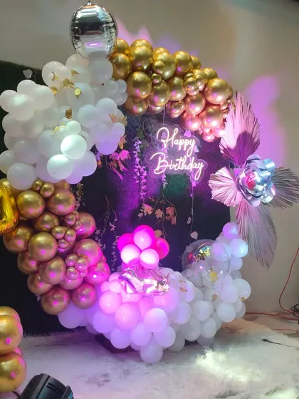 A closer look at the glamorous first birthday decor. The combination of gold and white balloons, a disco ball, and purple uplighting creates a festive and modern party vibe.