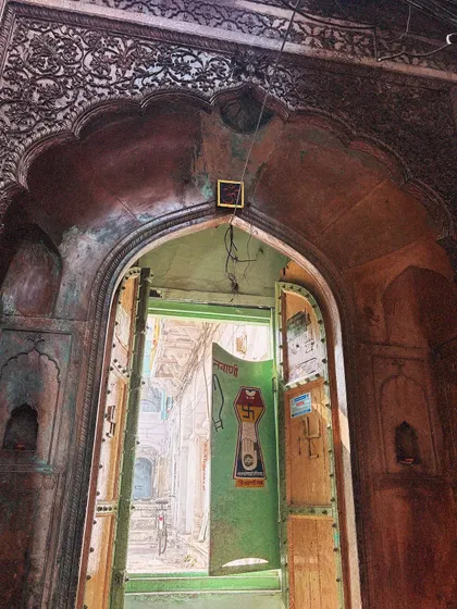 Looking through an intricately carved archway into a haveli's inner lane. This perspective gives a sense of the layers of history and life in Old Delhi.