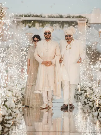 The groom's dapper entry with his parents at his Goa beach wedding. The mirrored aisle and sparklers made it a showstopper.
