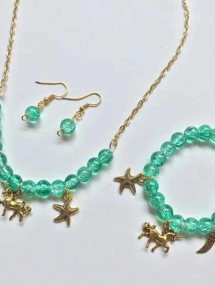 A different arrangement of the green charm necklace and bracelet set, showing its vibrant colour and playful design.