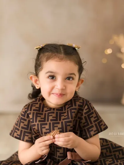 A charming close-up portrait of a little girl in a stylish dress. Her sweet smile and direct gaze make for a captivating image.
