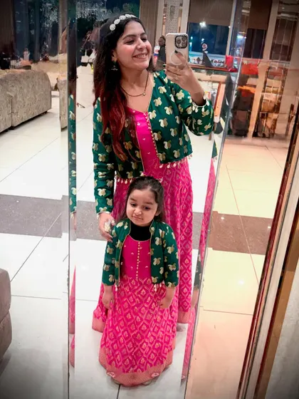 A mirror selfie showing off our matching mom-daughter outfits. This view highlights how the fabric from a single saree was used to create two complete, coordinated looks.