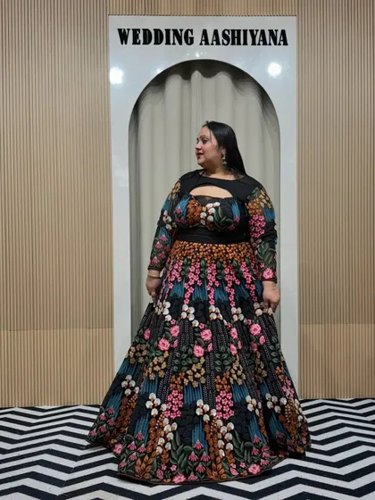 A beautiful plus-size client in a stunning black lehenga with colorful floral embroidery. The keyhole neckline and full sleeves make it a stylish and comfortable choice for any celebration.