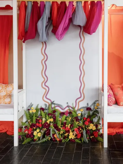 A symmetrical view of a decor element, featuring a floral arrangement at the base of a wall with elegant, wavy painted borders.