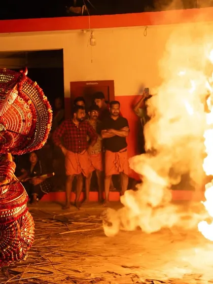 Close-up and action shots of the Kandanar Kelan Theyyam, focusing on the detailed costume, expressive mask, and the raw power of the fire performance.