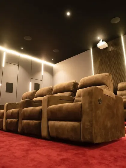 A view from the side, highlighting the tiered seating platform with integrated lighting and the carefully placed surround sound speakers for a true Dolby Atmos experience.