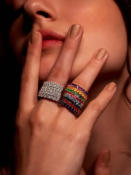 Bold statements for a confident style. Here, a hand wears two of my wide band rings: one fully encrusted with brilliant diamonds, the other a rainbow of vibrant gemstones. These pieces are for those who are not afraid to shine.