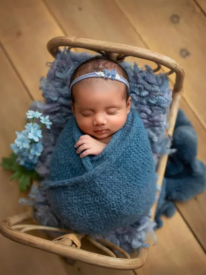 A beautiful shot from a recent workshop, showing a baby girl swaddled in blue on a tiny rattan bed.