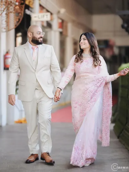 The couple shares a look of love as they walk hand-in-hand. This photo captures the movement and elegance of the bride's sari.