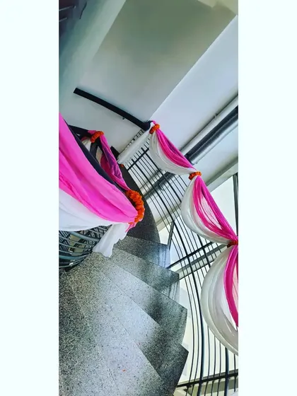 A simple way to add a festive touch to your home is by decorating the staircase. Here, I've used pink and white drapes with small marigold bunches to brighten up the railing for a house party.
