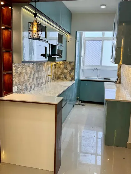 A beautiful kitchen design with teal cabinets and a patterned hexagonal tile backsplash. The white marble countertop and breakfast bar create a nice contrast.