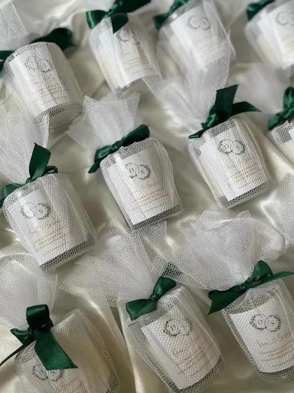 These votive candles are individually wrapped in net potlis with a custom tag, perfect for wedding favors. The emerald green ribbon adds a touch of luxury.