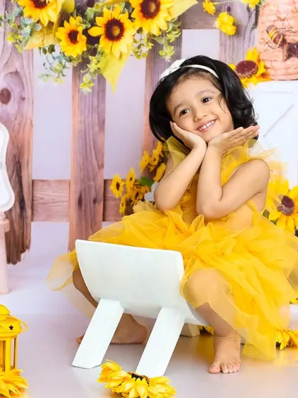 A sweet and precious pose. Surrounded by sunflowers, this little girl's charming expression makes for a beautiful birthday portrait.