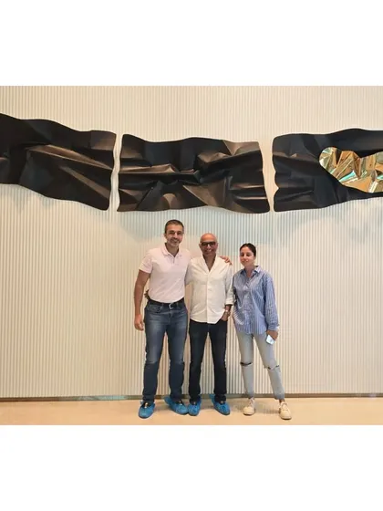 With the happy clients in front of their newly installed 13-foot custom wall sculpture.