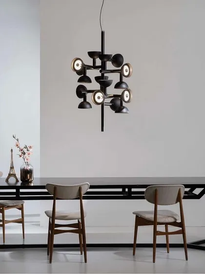 The Sibilla chandelier over a long dining table. Its creative geometric combination changes depending on the viewpoint, making it a dynamic and engaging fixture.