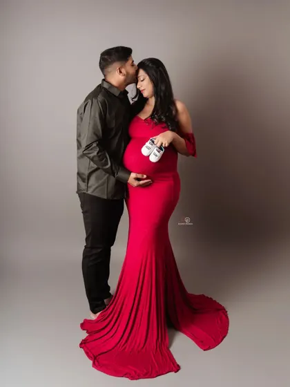 Waiting for their little miracle. This tender moment, with the dad-to-be kissing his partner's forehead while she holds tiny baby shoes, is what couple's maternity shoots are all about.
