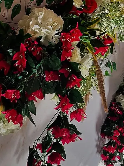 A detailed view of a floral arrangement, showcasing a vibrant mix of red bougainvillea and white carnations. The careful combination of colors and flower types is key to our design process.