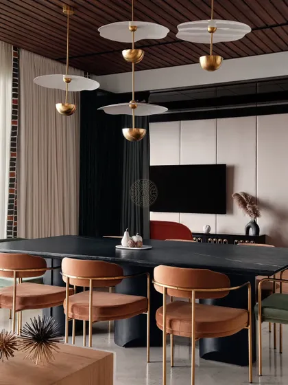 The dining table is set under unique pendant lights with white, petal-like shades and brass details. The dark table provides a grounding contrast to the lighter elements in the room.