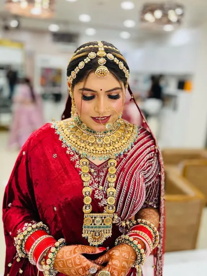 A beautiful shot of the bride looking down, highlighting the intricate eye makeup and the heavy traditional jewelry.