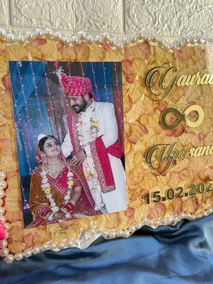 The infinity symbol between the names is a popular request, symbolizing eternal love. The golden text shines against the preserved petals.