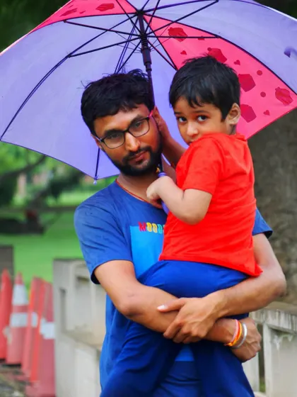 A closer portrait of the father and son under the umbrella. The child's curious gaze and the father's gentle hold make for an intimate family photograph.