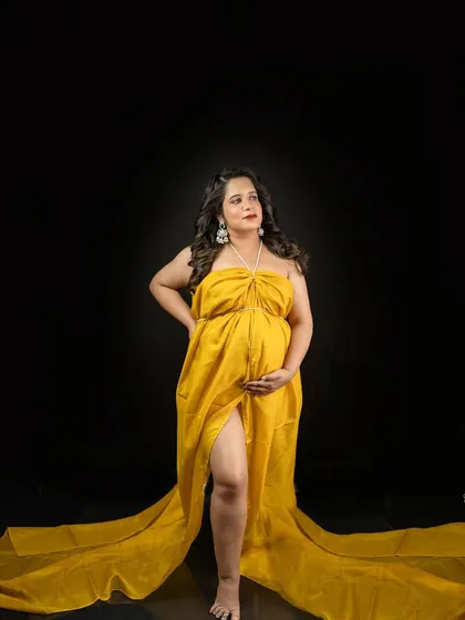A powerful stance against a classic black backdrop. The vibrant yellow gown creates a stunning contrast, making this a truly eye-catching maternity portrait.