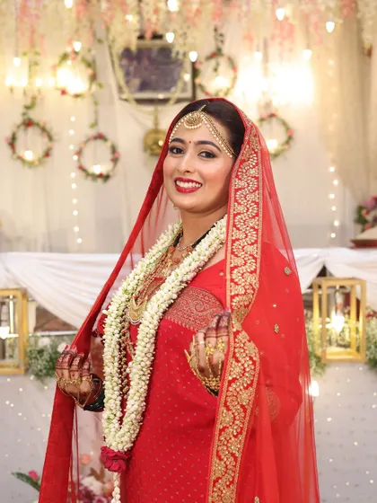A smiling portrait of a Coorgi bride, her face framed by her red veil. Her makeup is bright and joyful.