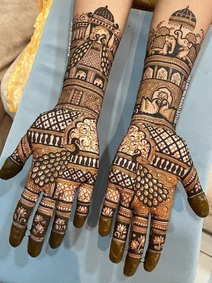A beautiful design featuring peacocks with full plumage on the palms and elephant motifs on the arms.