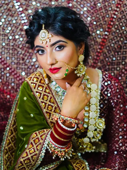 A confident portrait of the bride, showcasing the rich colors and textures of her outfit, perfectly complemented by the student's makeup.